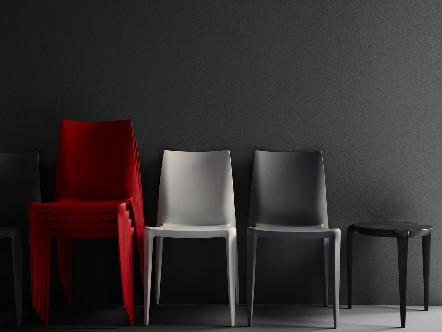 The Bellini Chair, 4 Red Stacked next to Light Grey and Dark Grey